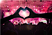 Hands forming a heart at a pink concert