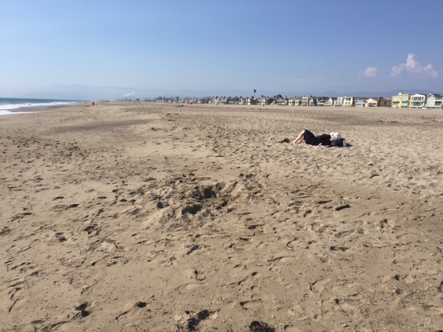 Harpist Anne Roos napping on a beach, without her harp